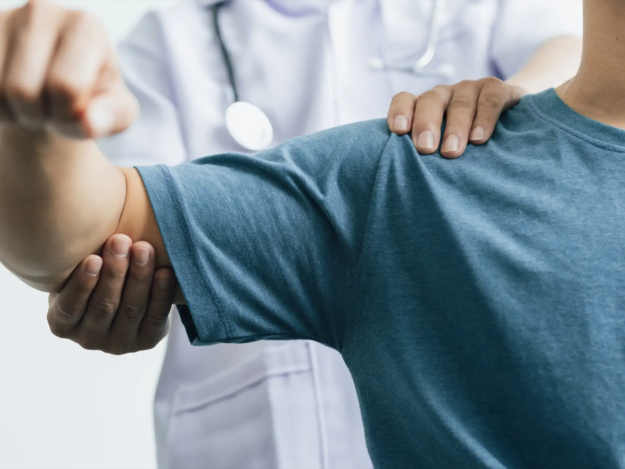 A healthcare professional guides a patient’s arm during a physical examination