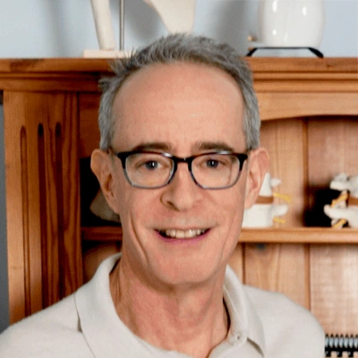 Jonathan Taylor wearing a light-colored collared shirt standing in front of a wooden shelf